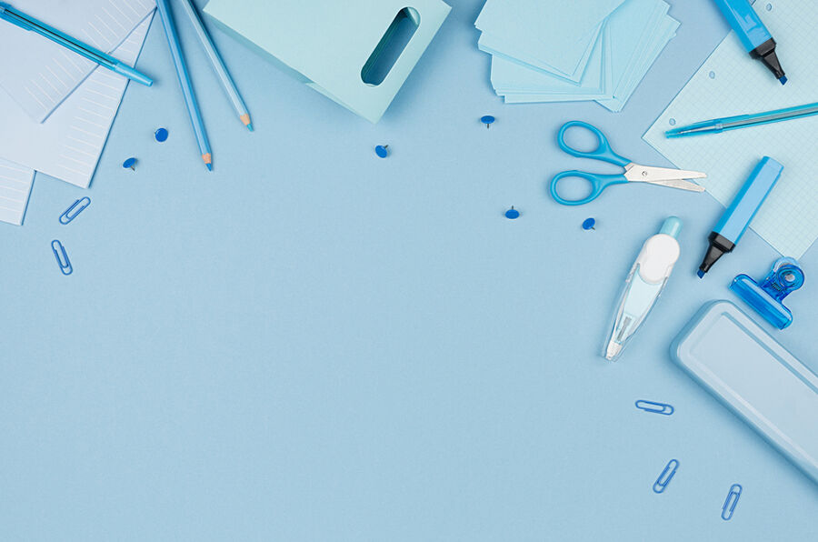 Pens, scissors and paper clips on a blue desk