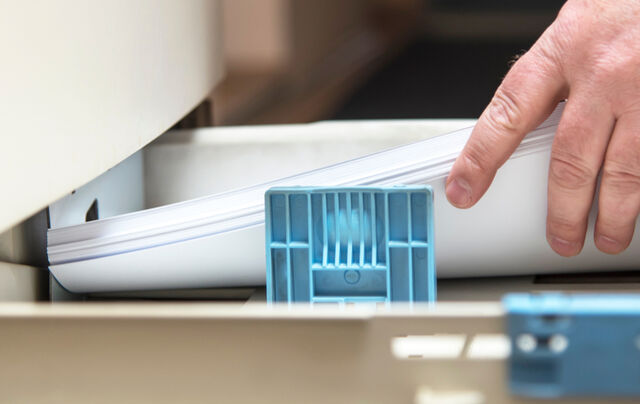 Hand loading paper into a printer tray